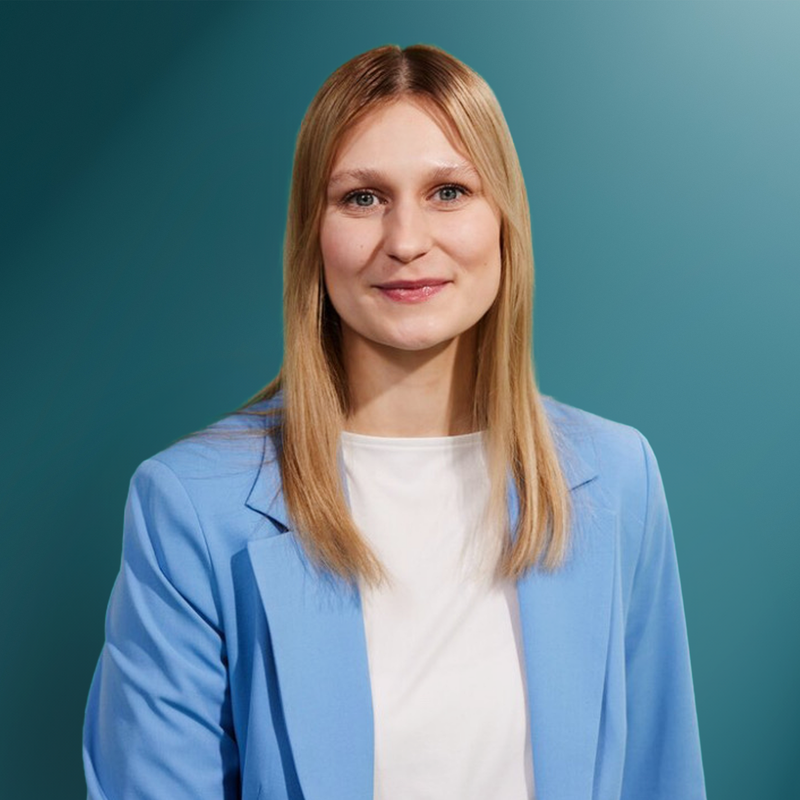 Eine lächelnde Frau mit langen, blonden Haaren trägt ein hellblaues Sakko über einem weißen Shirt vor einem sanft abgedunkelten Hintergrund