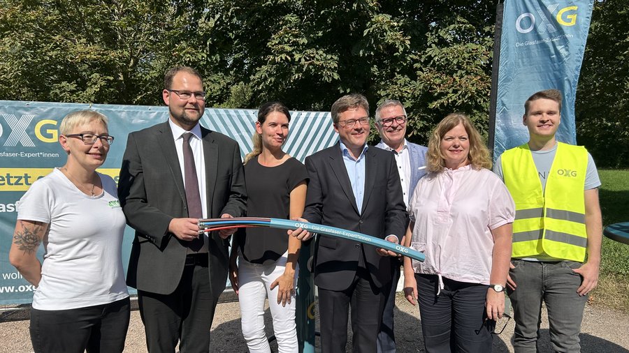 Gruppenbild von sieben Personen, die zusammen mit Glasfaserkabeln vor einem Banner der Firma OXG in der Stadt Eisenach stehen.