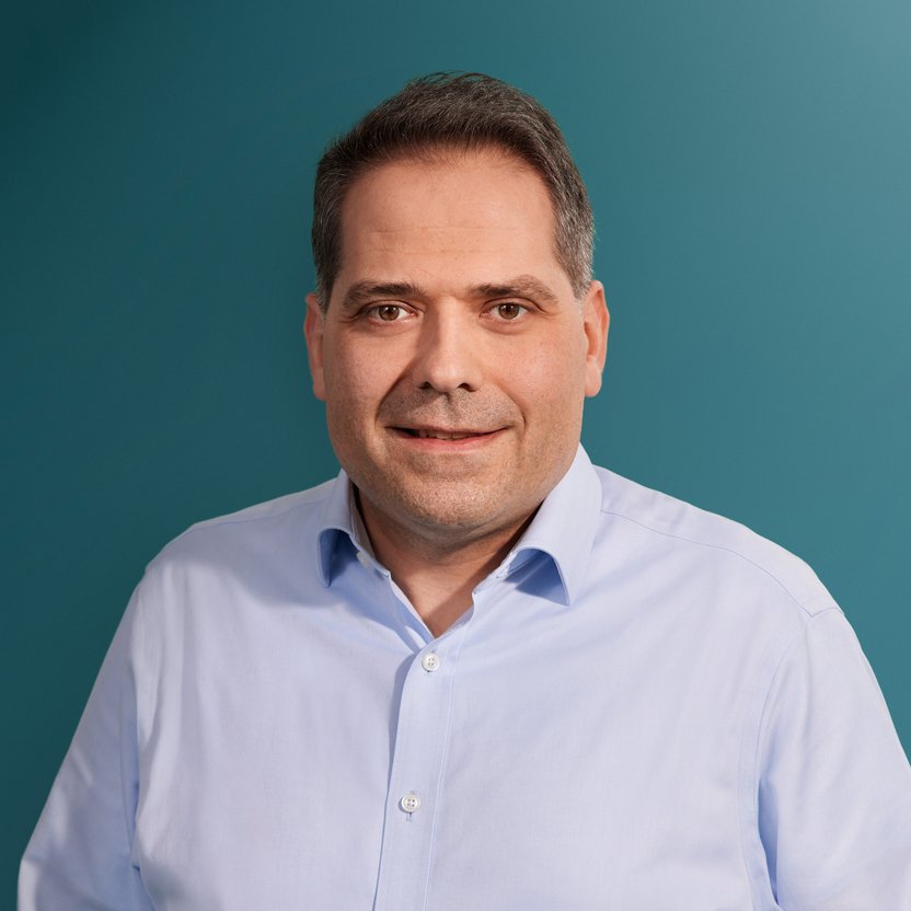 Mann mit Hemd, posiert vor einem hellblauen Hintergrund