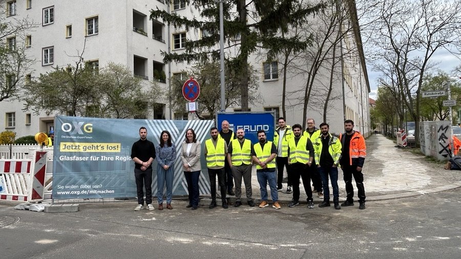 Gruppe von Personen in Sicherheitswesten vor einem Banner zur Glasfaserverlegung in der Stadt Lichtenberg