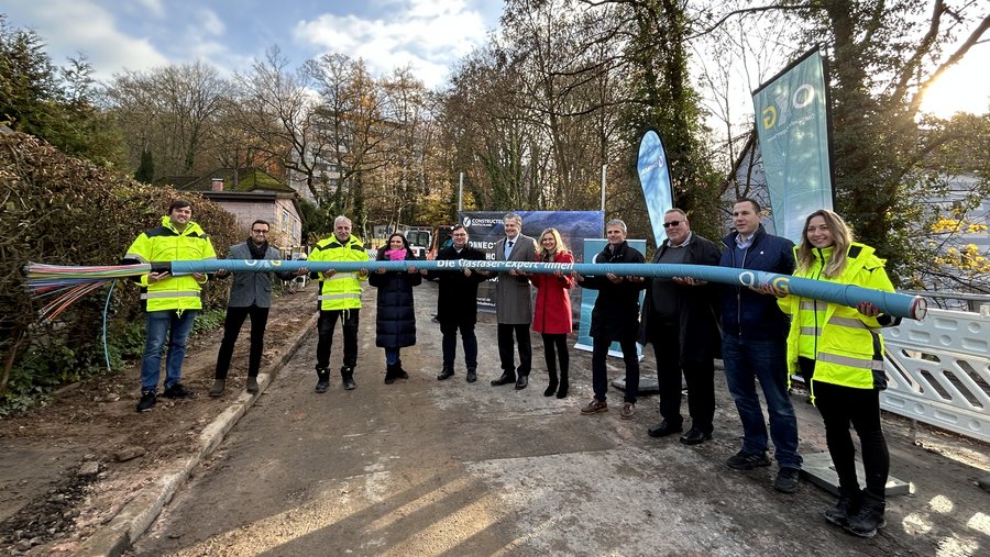 Ein Gruppenfoto von neun Personen, die gemeinsam ein großes, buntes Kabel halten, während sie in einer landwirtschaftlichen Umgebung in Marburg mit Bäumen im Hintergrund stehen