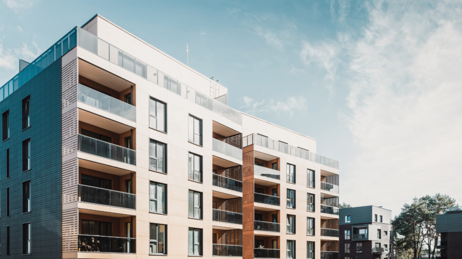 Moderne Wohnanlage mit mehreren Etagen, großzügigen Balkonen und einer modernen Fassade aus verschiedenen Materialien unter blauem Himmel
