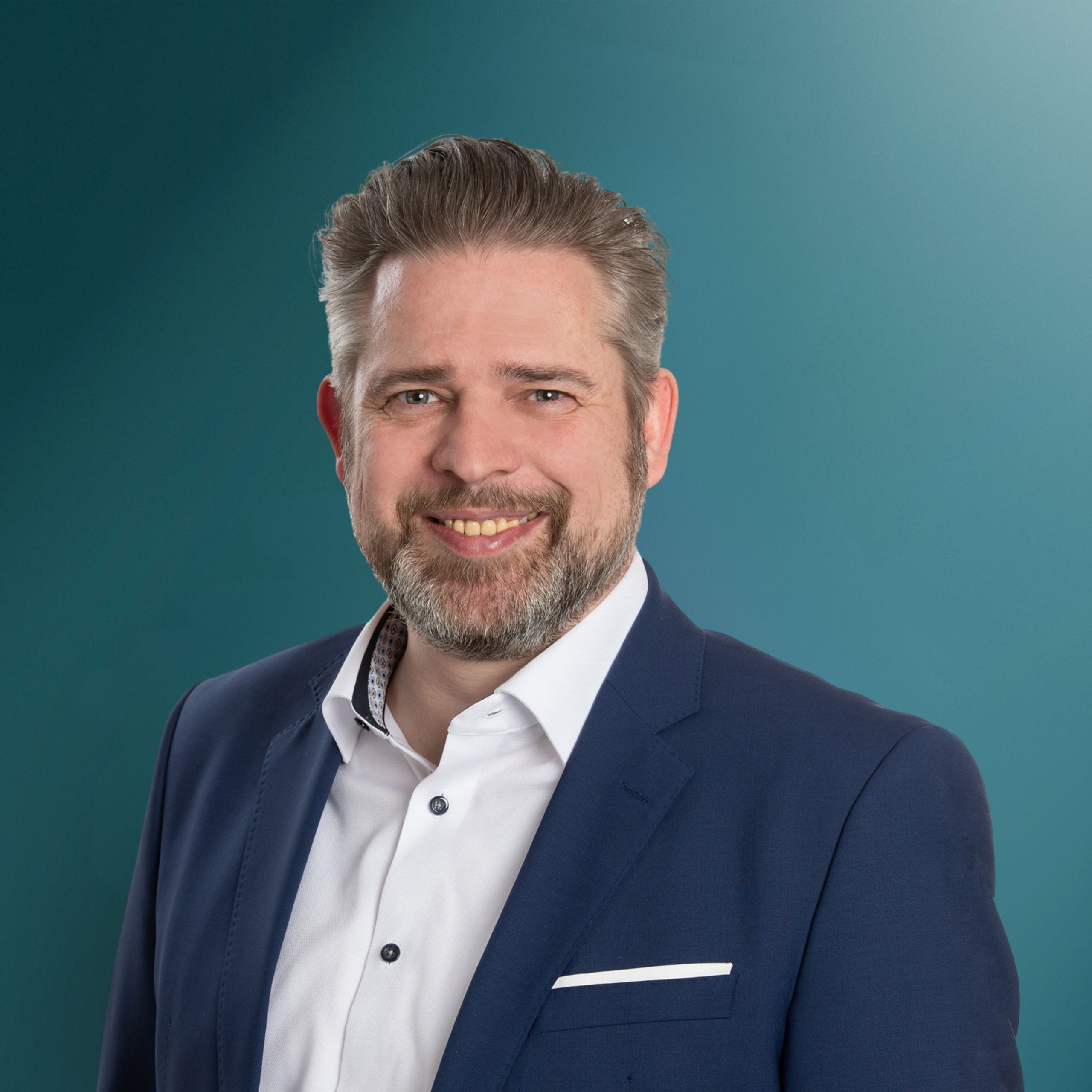 Ansprechpartner für OXG Glasfaser in der Wohnungswirtschaft, posiert in einem Anzug vor einem einfarbigen Hintergrund